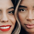 Two female friends up close, cheek to cheek.
