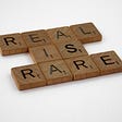 scrabble tiles spelling out “real is rare”