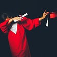 A person in a red graduation gown dabbing with a diploma and cap in their hands.