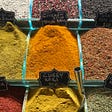 A selection of spices, piled up, with names and prices on small black labels in a spice market in Istanbul