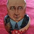 The photo is a matryoshka (Russian nesting) doll with the face and body of Vladimir Putin with a red background.