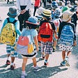 Young children walking to school with their supplies