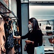 Woman with a mask shopping for clothes in a store