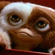 A gremlin from the movie looking up in a cute fashion