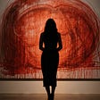 Sillouette of a woman standing in a front of a large abstract painting