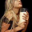 a woman in ecstasy, clutching a glass of milk to her chest.