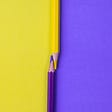 Purple and yellow crayons resting on purple and yellow background