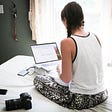 Girl in pyjamas sitting on the bed with laptop.