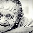 Black and white photo of a smiling, toothless elderly woman.