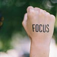 A person with the word focus written on her fist