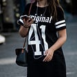 A young woman putting all her attention into her smartphone, as she walks down the street.