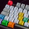 Computer keyboard with colourful keys sitting on a dark background.