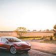 red tesla against a sunset background