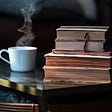 A cup of coffee and a stack of books on a table