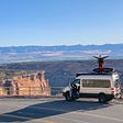 Picture of a man standing on the roof of his sprinter van overlooking a canyon