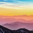 Mountain climber on the pick of a mountain at sunrise. Colorful background