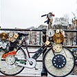 Bicycle covered with clocks, parked on a low bridge over a canal