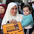 Woman holding a young child and a sign