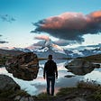 man standing on a lake where big rocks swim, sky with clouds