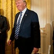 President Donald Trump, center, accompanied by Vice President Mike Pence, right, arrives for a White House senior staff swearing in ceremony in the East Room of the White House, Sunday, Jan. 22, 2017, in Washington. (AP Photo/Andrew Harnik)