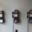 Three payphones hanging from the wall.