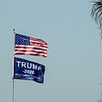 A “Trump 2020” flag flies beneath an American flag