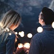 Man and woman talking under string lights outside