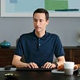 man in navy shirt typing at computer