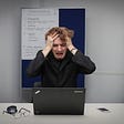 Frustrated student holding his head and looking at a laptop screen