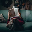 [Girl reading book on couch]