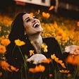 A girl laughing in between a flower garden