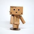 A figure made out of Amazon boxes, with a sad face oriented to the camera