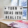 A whiteboard that says “Turn ideas into reality”, leads to meaning in terms of business and good vibes.