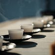 A line of traditional tea cups with steam rising