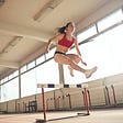 Woman leaping over hurdle