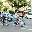Woman riding a share bike in a city.