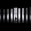 Silhouette of a blurred human carrying a bag framed in one pane while walking through a black and white field of jagged, slender, fogged, separate vertical panels which are surrounded in black