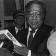 A photo of author Alex Haley holding a copy of his book, “Roots”