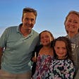 Author, the dad, and his wife and two school aged children smiling for a family photo with a sunset behind them.