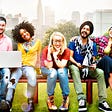 Six happy and diverse people sitting together on a bench