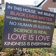 Photo of a black yard sign with colorful progressive believes stated.