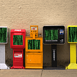 A row of newspaper boxes on a lonely sidewalk; their windows are filled with the ‘falling binary’ Matrix waterfall effect.