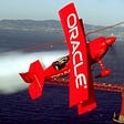 Picture of a Red airplane above the red bridge of San Francisco with the word oracle.
