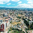 Aerial overview of Addis Ababa with blue skies. The city sprawls into the distance, with rolling mountains far away.