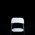 A image of a white chair standing empty against a black background