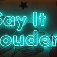 A neon sign reading “Say It Louder!” hangs on a wall painted with large flowers and stars.