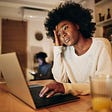 An African American woman freelancer working on a laptop, looking stressed
