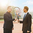 photo of two business man holding a racquet.