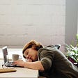 Overachieving woman sitting at her desk on her computer working too hard. She’s experiencing fear of failure.