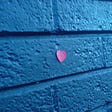 loveheart stuck to a blue brick wall